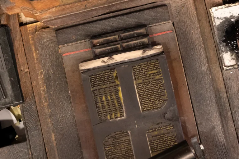Blick von oben auf eine alte Handdruckpresse mit gesetzter Druckform auf dunklem Holz